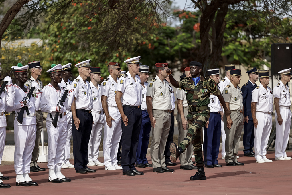 جندي سنغالي يمرّ أمام أفراد من الجيش الفرنسي قبيل حفل تُسلِّم آخر قاعدة عسكرية (أ ف ب)