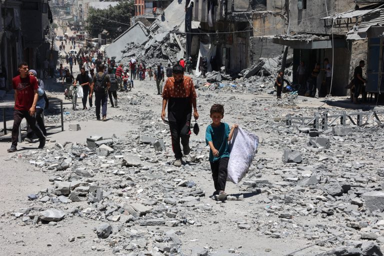 فلسطينيون يسيرون أنقاض مبانٍ دُمّرت جراء غارات إسرائيلية على حي الدرج في غزة (أ ف ب)