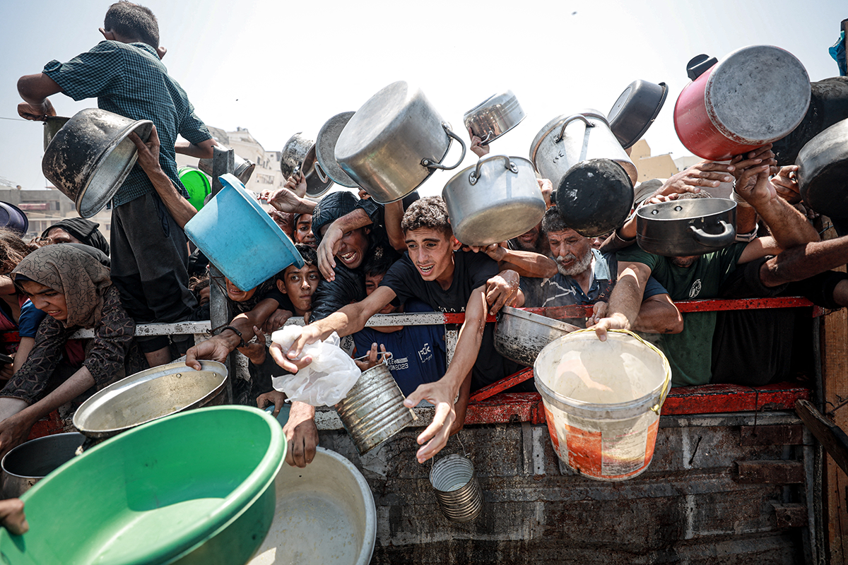 فلسطينيون يتجمعون للحصول على وجبات ساخنة توزعها منظمات الإغاثة في غزة (أ ف ب)