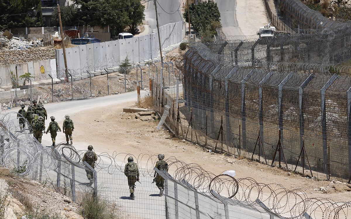 جنود إسرائيليون يمشون على الحدود مع سوريا بالقرب من بلدة مجدل شمس (أ ف ب)