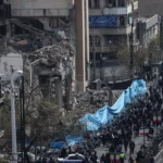 إيرانيون يسيرون أمام مبنى مدمر في طهران (أ ف ب)