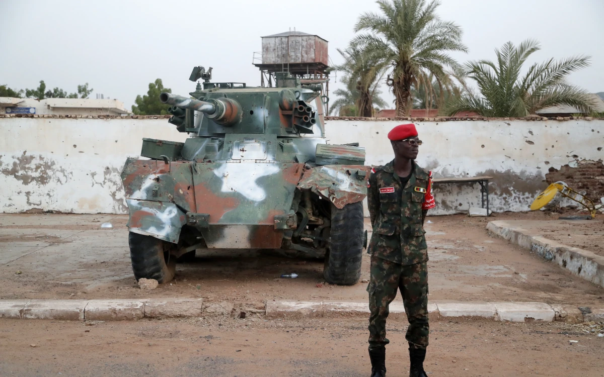 جندي من الجيش السوداني يقف أمام دبابة متضررة جراء المعارك بين الجيش السوداني وقوات الدعم السريع.