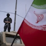 ضابط شرطة إيراني مسلح يراقب مسيرة تديرها الدولة في طهران (أ ف ب)