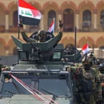 جندي عراقي وسط عناصر أخرين يرفع علامة النصر خلال الاحتفال بمناسبة انسحاب القوات الأمريكية (أ ف ب)