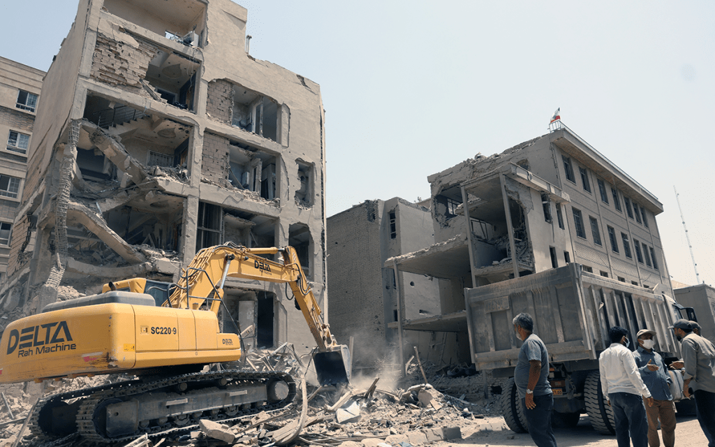 An excavator clears rubble in front of a building hit by Israeli strikes in Tehran