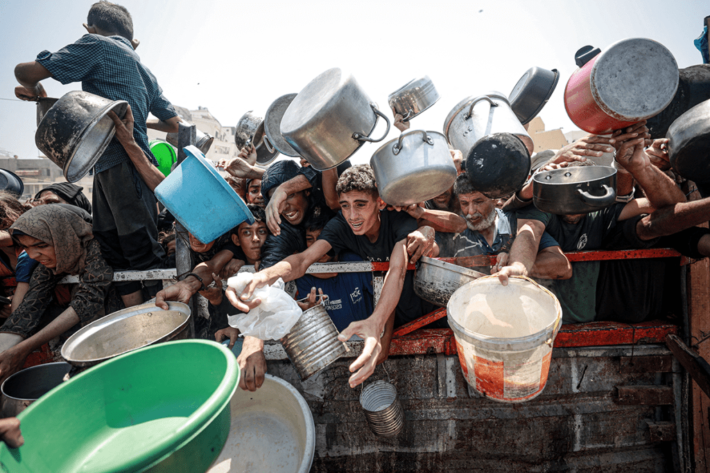 Palestinians gather to receive hot meals distributed by aid organizations in Gaza