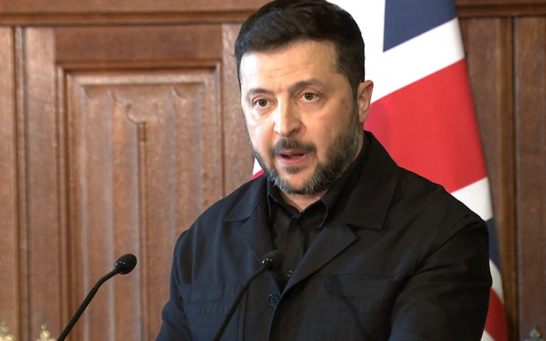 Ukraine President Volodymyr Zelensky speaking in fron of a UK flag