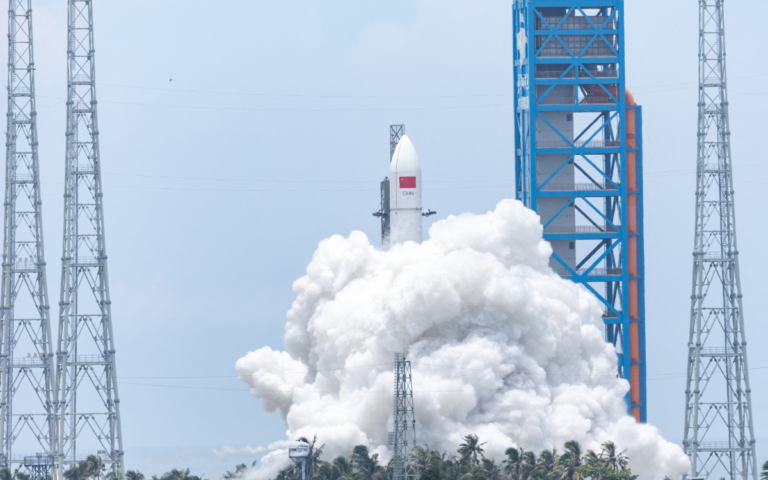 A white rocket with the Chinese flag can be seen launching into the sky with a lot of smoke at the bottom.