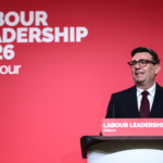 Burnham Set for Prime Minister as UK Enters New Era Andy Burnham giving a speech at a desk in front of a red background which reads "Labour Leadership 2026"