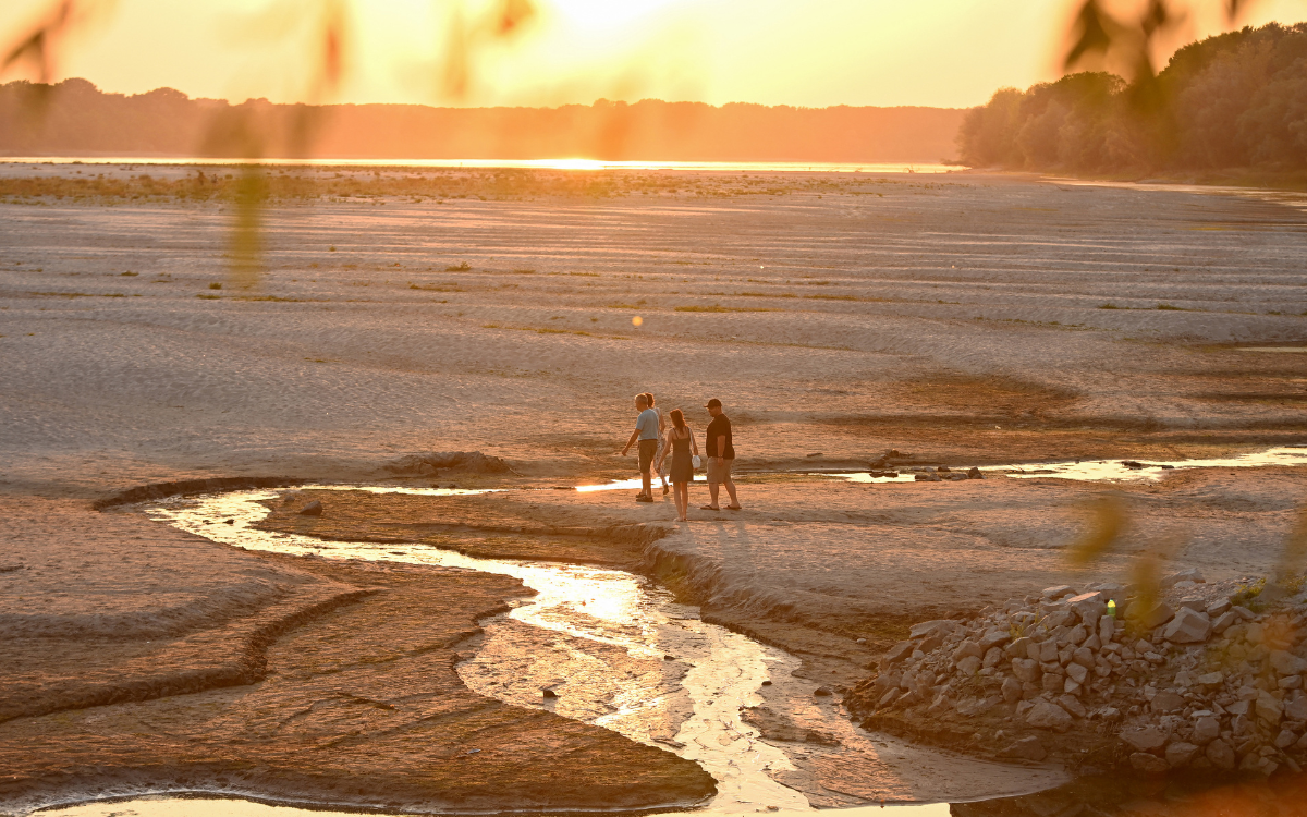 People walk across sandbars exposed by the low water level of the Danube River in Serbia.