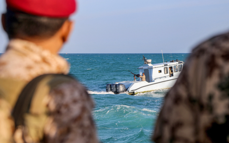 Yemeni coastguard members loyal to the internationally-recognised government observe as others ride in a patrol boat in the Red Sea off of the government-held town of Mokha in the western Taiz province, close to the strategic Bab al-Mandab Strait