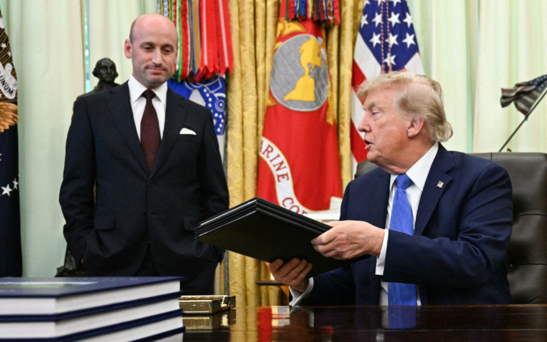 White House Deputy Chief of Staff Stephen Miller (L) smiles as US President Donald Trump holds signed executive orders in the Oval Office of the White House in Washington, DC