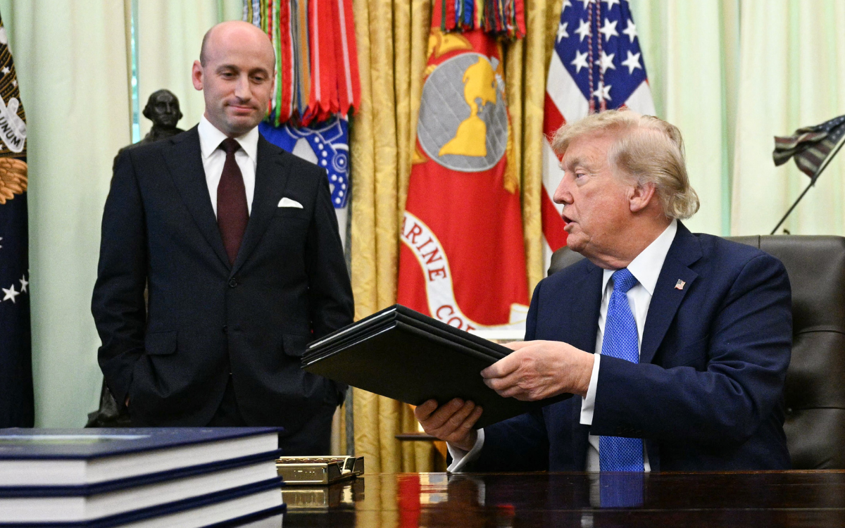 White House Deputy Chief of Staff Stephen Miller (L) smiles as US President Donald Trump holds signed executive orders in the Oval Office of the White House in Washington, DC