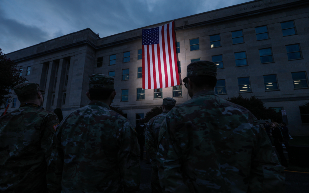 Military personnel and first responders watch as an American flag is raised alongside the Pentagon